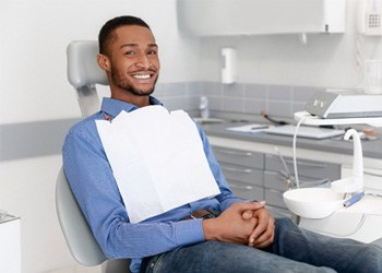 Man in blue shirt sitting in dental chair waiting for amalgam filling removal in Cumberland