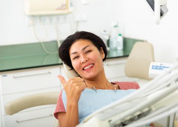 Female dental patient giving a thumbs up